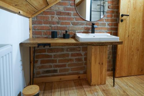 a bathroom with a sink and a brick wall at Lawki Booking-Na Strychu in Ławki