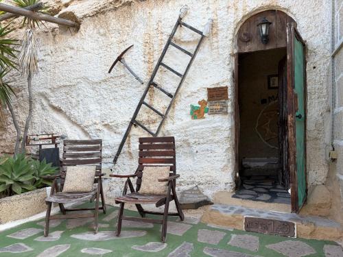 two chairs sitting in front of a building with a ladder at Casas Cueva Alfer in Fasnia