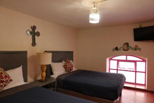a bedroom with two beds and a cross on the wall at Rinconcito de Galarza 28 in Guanajuato