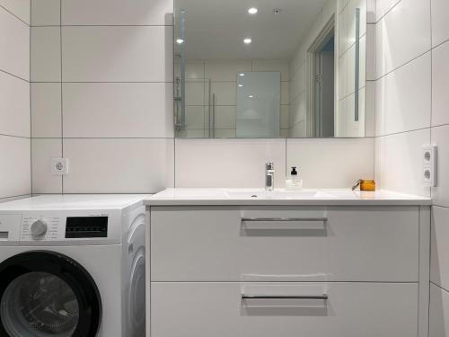 a white bathroom with a washing machine and a sink at Bryggebyen in Arendal