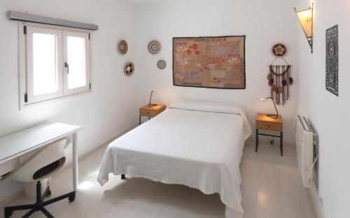 a white bedroom with a bed and a desk and a window at La Estrella de Tarifa in Tarifa