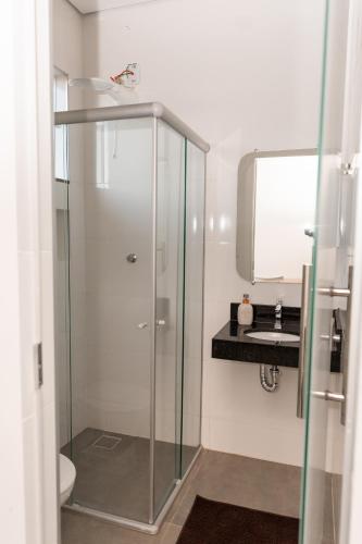 a bathroom with a glass shower and a sink at Lagoa Suítes in Lagoa Santa