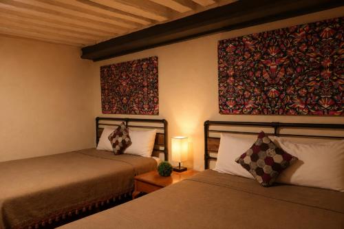 a bedroom with two beds and a painting on the wall at Escondite de Galarza 26 in Guanajuato