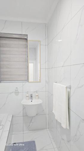 a white bathroom with a sink and a shower at HMT Guest House in Thohoyandou