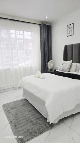 a white bedroom with a large bed and a window at HMT Guest House in Thohoyandou
