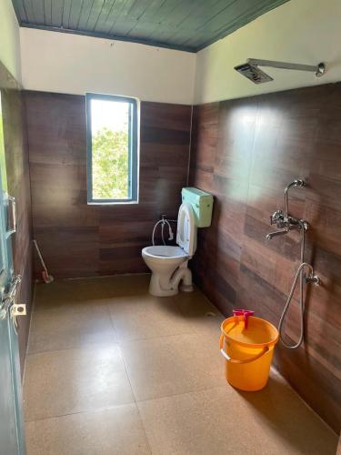 a bathroom with a toilet and a shower and a bucket at Prathmesh Homestay in Bijanbāri Bāzār