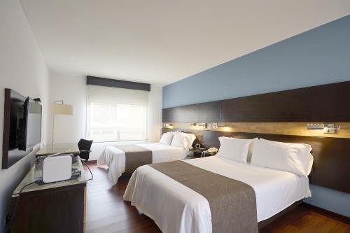 a hotel room with two beds and a flat screen tv at Mercure Bogota BH Retiro in Bogotá