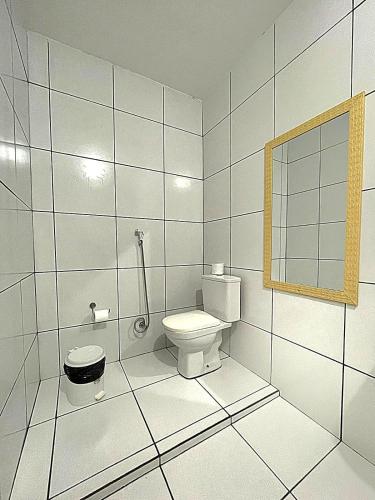 a white bathroom with a toilet and a mirror at Pousada Nativ0s in Baía Formosa