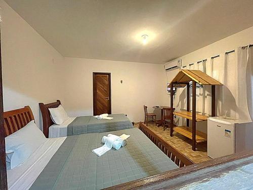 a hotel room with two beds and a table at Pousada Nativ0s in Baía Formosa