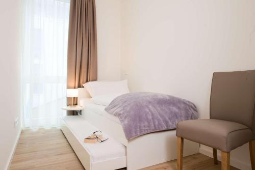 - une petite chambre avec un lit et une chaise dans l'établissement Südkap F-02, à Pelzerhaken