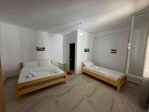a white bedroom with two beds and a window at Lukova rooms in Lukovë