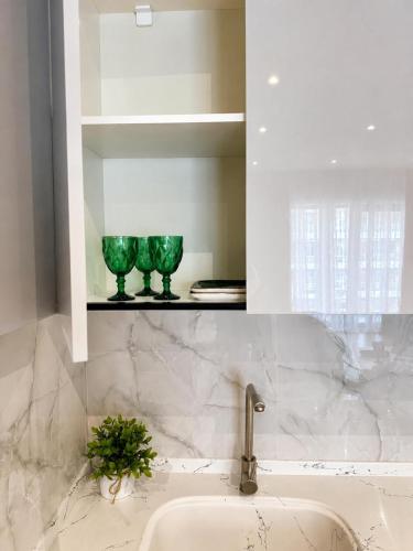 a bathroom with a sink and two green glasses on a shelf at Sea Breeze Apartments in Baku