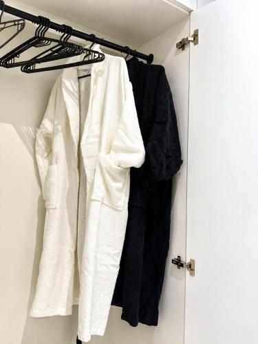 a closet with white and black clothes on a rack at Sea Breeze Apartments in Baku