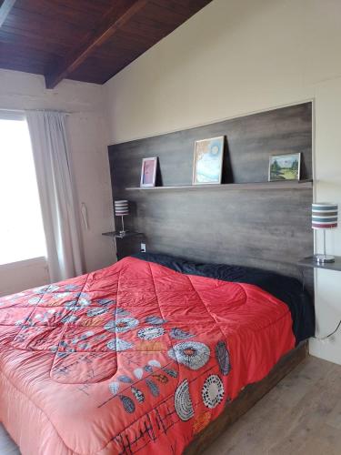 a bedroom with a red bed with a wooden headboard at Talita Cumi in Villa Santa Cruz del Lago