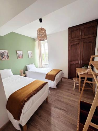 two beds in a room with green walls and a table at L'écrin d'Hélène in Lormes
