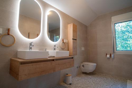 a bathroom with two sinks and a toilet and mirrors at Holiday Home Ari in Lički Ribnik