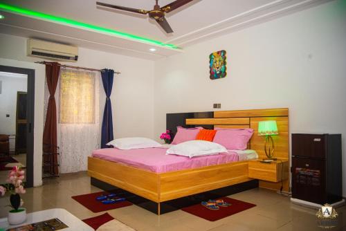a bedroom with a large bed with pink sheets at Hôtel Akwin Kpalimé in Palimé
