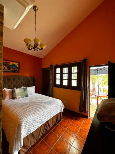 a bedroom with orange walls and a bed and a window at La Posada de Don Manuel in Santiago Sacatepéquez