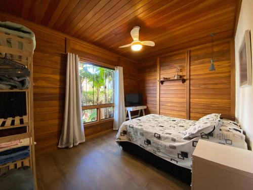 a bedroom with a bed in a wooden room with a window at Paz e Conforto na Serra Pet Friendly in Teresópolis