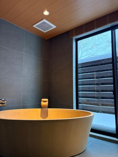 a bath tub in a room with a large window at KOMU Hakuba in Hakuba