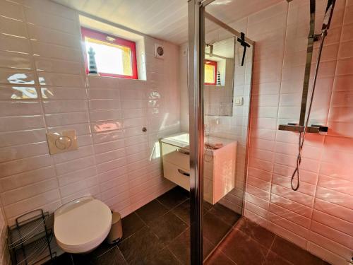 a bathroom with a toilet and a shower with pink tiles at Les Petits Champs Islandais in Manas-Bastanous