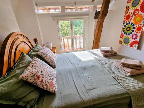 a bedroom with a large bed with pillows and a window at Les Petits Champs Islandais in Manas-Bastanous