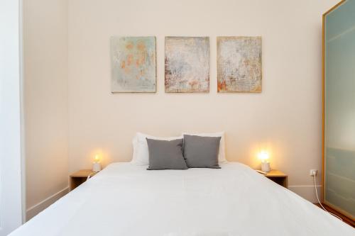 a bedroom with a white bed and three paintings on the wall at Lisbon Design Flat, Luxury, 7 People, Pool Garden in Lisbon