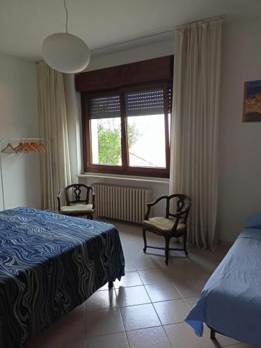 a bedroom with a bed and two chairs and a window at Appartamento in villa con vista Monviso in Piossasco