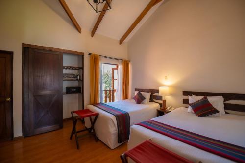 a hotel room with two beds and a window at Hotel San Agustin Urubamba in Urubamba