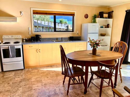 a kitchen with a wooden table with chairs and a refrigerator at The Shed in Manapouri