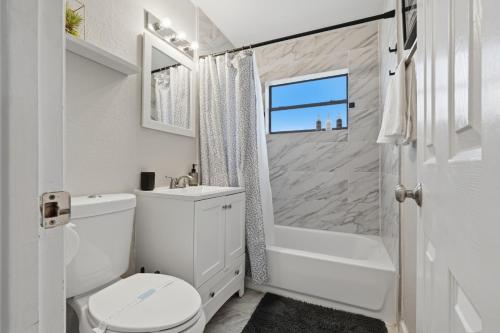 a white bathroom with a toilet and a shower at Amazing 2BR Queen 8mins SODO & 4mins ORMC in Orlando