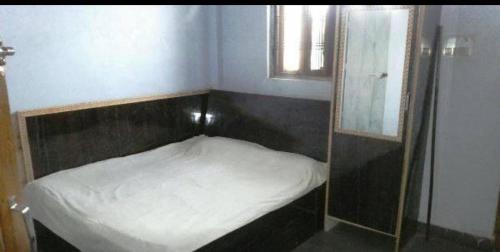 a small bed in a room with a mirror at Hotel motishree in Vidisha