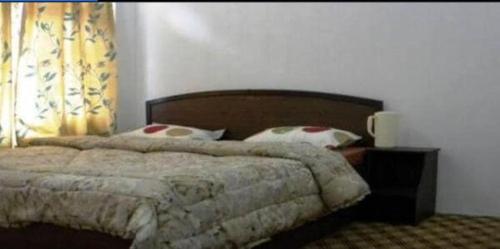 a bedroom with a bed with a wooden headboard and pillows at Hotel motishree in Vidisha