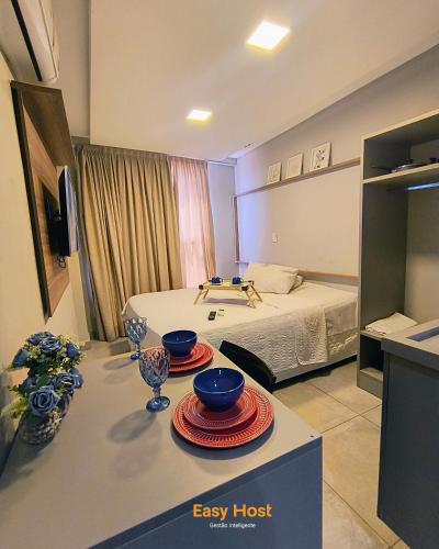 a room with a bed and a table with bowls on it at Uno Flats - By EasyHost in Tambaú
