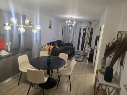 a living room with a table and chairs and a couch at Havre de paix confort,élégance in Chelles