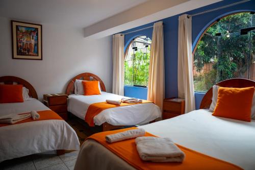 a room with three beds with orange and white at Luz y Amistad - Pisac in Pisac