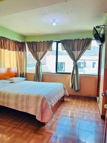 a bedroom with a bed and a large window at Hostal acacias in Cuenca