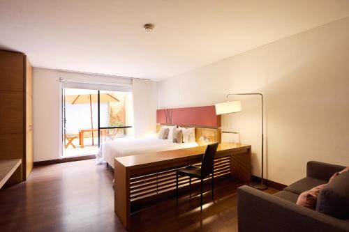 a hotel room with a bed and a desk with a chair at Hotel bh La Quinta in Bogotá