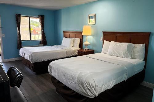 two beds in a hotel room with blue walls at Mountain View Inn Irvine Near Richmond KY in Irvine