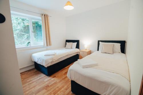 two twin beds in a room with a window at The Coastal Breeze in Porthmadog