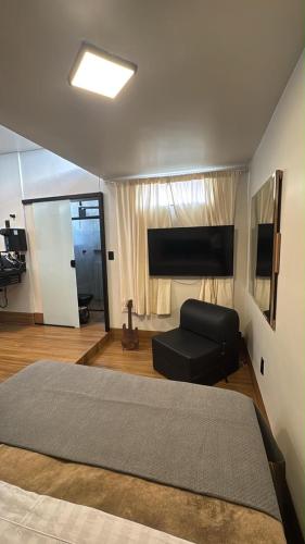 a bedroom with a large bed and a flat screen tv at 4 Studio novo no centro com ar condicionado e tv UFLA, UNILAVRAS restaurantes padaria in Lavras
