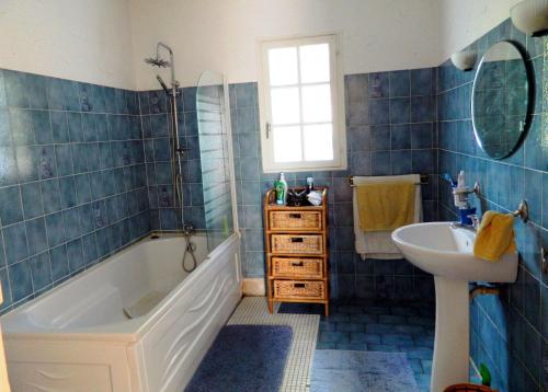 La salle de bains est pourvue de carrelage bleu, d'une baignoire et d'un lavabo. dans l'établissement Les Lauriers, à Limoux