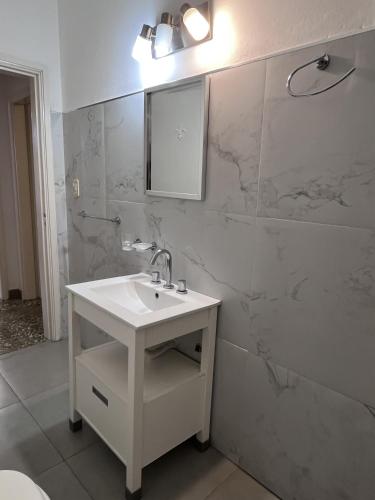 a white bathroom with a sink and a mirror at Lomar Apart 2 - Depto céntrico Villa María in Villa María