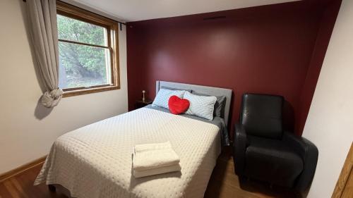 a bedroom with a bed with a red pillow and a chair at Cabernet Sauvignon Escape in Calgary