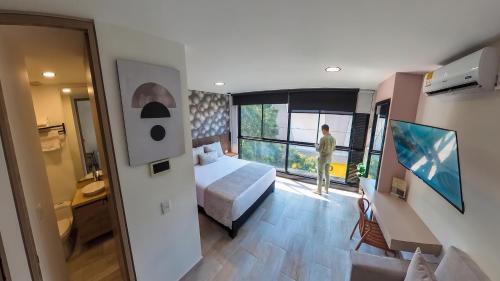a hotel room with a bed and a man looking out the window at Hotel Molinos by Growing Group in Medellín