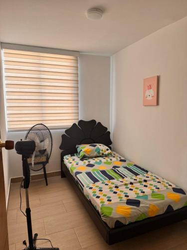 a bedroom with a bed and a fan and a window at Apto acogedor en Ibague in Ibagué