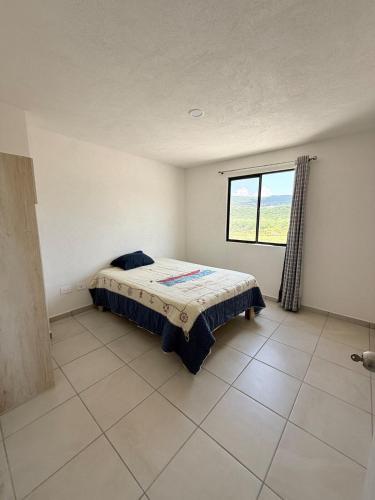 a bedroom with a bed in a room with a window at Bello departamento iluminado ideal para descansar in Querétaro