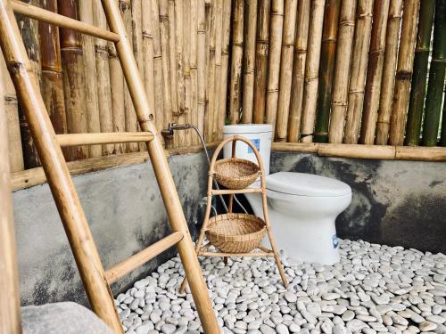 a bamboo bathroom with a toilet and two baskets at Rafka Bamboo Valley in Seribatu