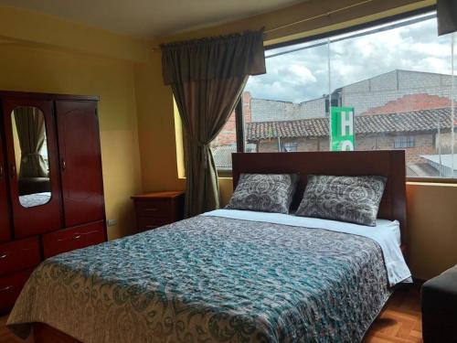a bedroom with a bed and a large window at Hostal acacias in Cuenca
