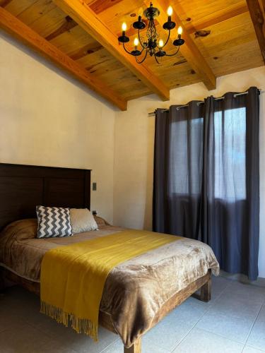 a bedroom with a large bed with a chandelier at Cabaña el roble, Mazamitla Jalisco in Mazamitla